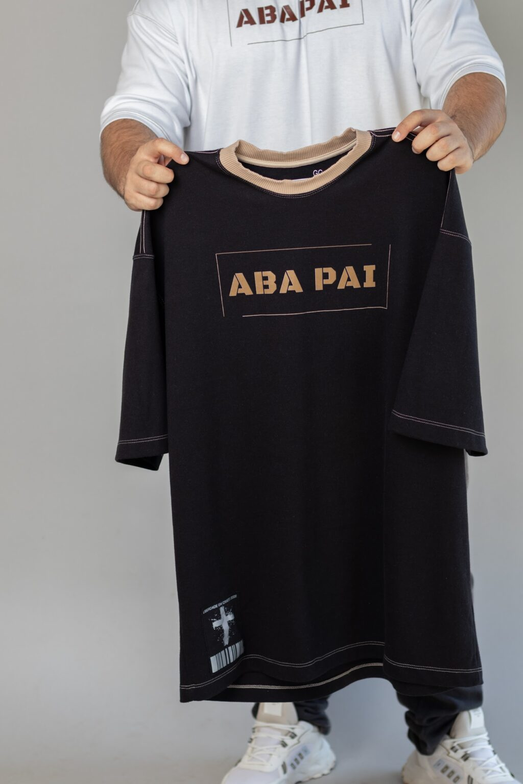 Mãos segurando a camiseta Aba Pai preta